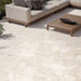 Contemporary outdoor patio featuring Jeddah Avorio Terrazzo 20mm 100x100cm outdoor stone-effect porcelain tile slabs, showcasing warm ivory and beige tones, paired with minimalist lounge seating, timber furniture and landscaped gardens.