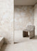 Interior featuring Jeddah Blanco Neutra Stone 30x60cm stone-effect wall and floor tiles, showcasing soft cream and ivory tones with natural stone-inspired detailing, paired with a sculptural stone chair in a minimalist contemporary space.
