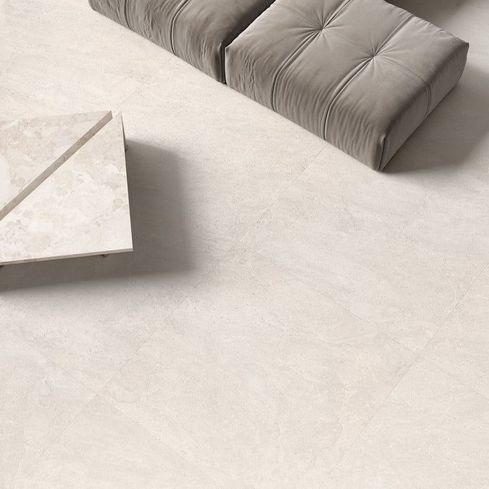 Contemporary living space featuring Jeddah Blanco Neutra Stone 60x60cm stone-effect wall and floor tiles, showcasing soft cream and ivory tones, paired with minimalist furniture, floor-to-ceiling glazing and warm natural textures.