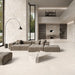 Contemporary living space featuring Jeddah Blanco Neutra Stone 60x60cm stone-effect wall and floor tiles, showcasing soft cream and ivory tones, paired with minimalist furniture, floor-to-ceiling glazing and warm natural textures.