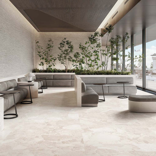 Contemporary lounge featuring Jeddah Blanco Sassi Terrazzo Stone 60x120cm stone-effect floor tiles, showcasing soft cream and beige tones with natural stone-inspired detailing, paired with minimalist seating, indoor planting and floor-to-ceiling glazing.