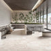 Contemporary lounge featuring Jeddah Blanco Sassi Terrazzo Stone 60x120cm stone-effect floor tiles, showcasing soft cream and beige tones with natural stone-inspired detailing, paired with minimalist seating, indoor planting and floor-to-ceiling glazing.