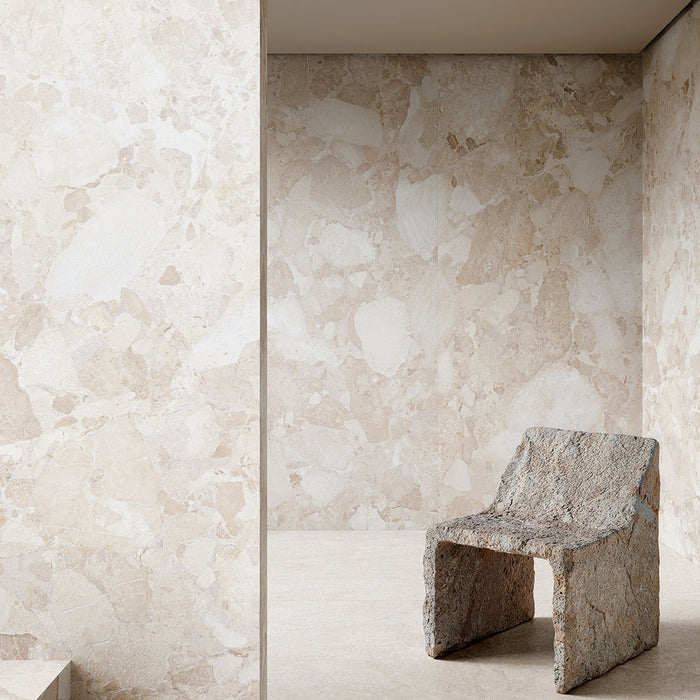 Interior featuring Jeddah Blanco Sassi Terrazzo Stone 60x60cm stone-effect wall and floor tiles, showcasing soft cream and beige tones with natural stone-inspired detailing, paired with a sculptural stone chair for a minimalist design.