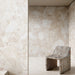 Interior featuring Jeddah Blanco Sassi Terrazzo Stone 60x60cm stone-effect wall and floor tiles, showcasing soft cream and beige tones with natural stone-inspired detailing, paired with a sculptural stone chair for a minimalist design.