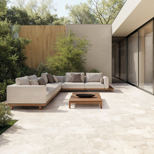 Contemporary outdoor patio featuring Riad Blanco Terrazzo 20mm 100x100cm outdoor stone-effect porcelain tile slabs, showcasing soft cream and beige tones, paired with minimalist lounge seating, timber furniture and landscaped gardens.