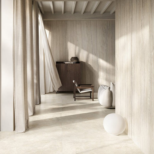 Living room featuring Jesi Travertine 60x60cm wall and floor tiles, showcasing soft travertine effect surfaces in warm cream and beige tones, paired with natural wood furniture, flowing linen curtains and minimalist styling for a calm, contemporary interior.
