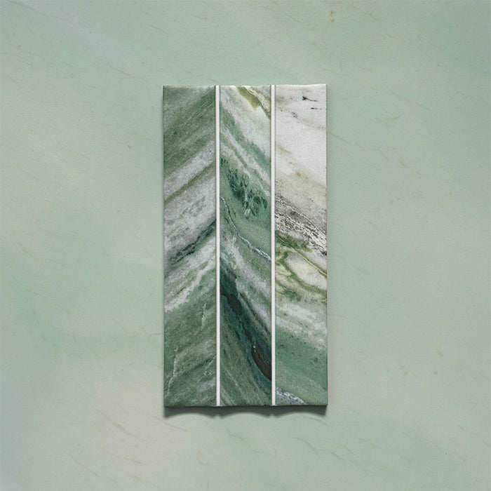 Product display of Kalamata Fluted Green Matt 11.5x23cm wall tiles in rich green marble-effect tones, featuring fluted detailing with natural veining against a soft green stone-effect backdrop.
