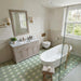 Bathroom featuring Kasuf Verde 20x20cm terrazzo-style decor floor tiles, styled with soft sage green tones, a freestanding bath, and brushed brass fixtures for a calming contemporary interior with a subtle geometric feel.