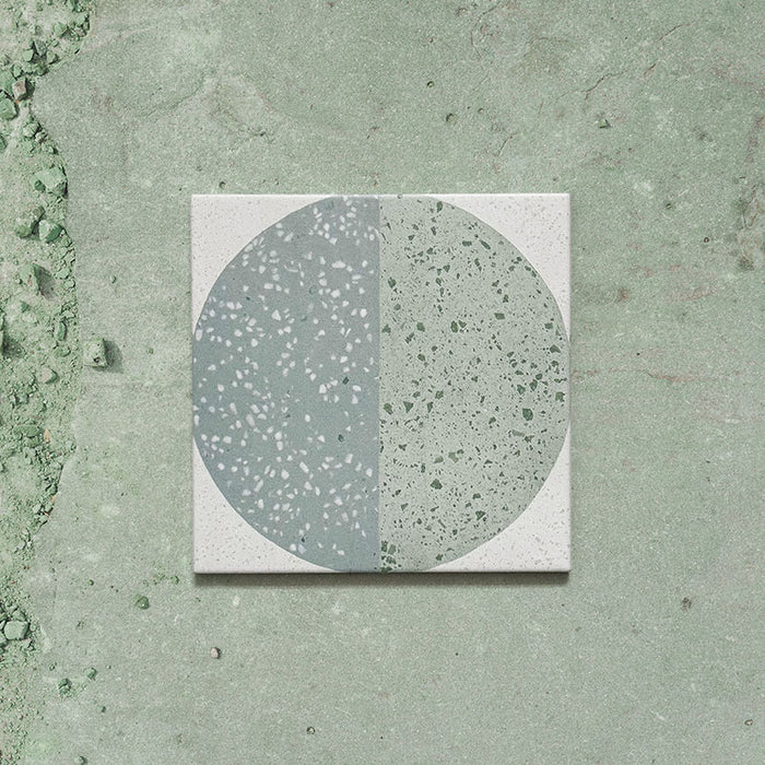 Kasuf Verde 20x20cm terrazzo-style decor tiles featuring a soft sage green and pale blue circular pattern with speckled terrazzo detailing, perfect for creating calming geometric floors and contemporary statement interiors.