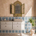 Bathroom featuring Kazhan Star Navy Blue 20x20cm Moroccan-style patterned wall tiles, paired with textured beige walls, a floating vanity, decorative carved mirror and terrazzo-effect floor tiles.