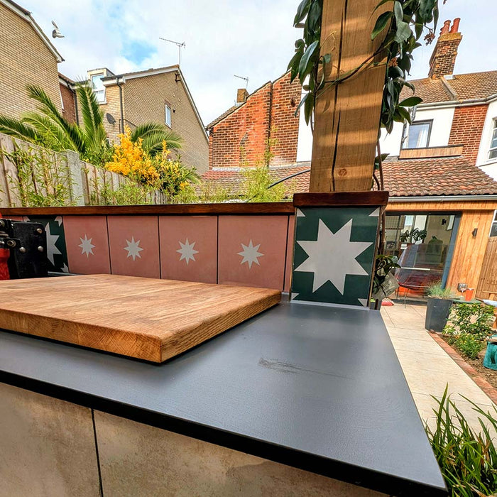 Outdoor garden bar featuring Kenitra Green Star 20cm x 20cm Moroccan style tiles, showcasing bold green and white star motifs alongside coordinating pink patterned tiles, timber details and surrounding greenery.