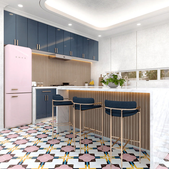 Geometry Contour patterned tiles in a 20x20cm size featured in a modern kitchen setting, showcasing pink circular motifs, mustard and teal linear accents, and brown geometric details on a light background. The tiles complement navy cabinetry, a pastel pink fridge, marble countertops, and gold-framed bar stools for a bold and colourful interior design.