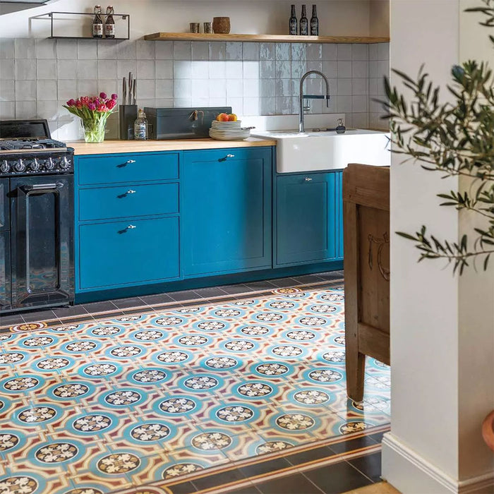 Kitchen interior featuring Europa Helsinki 20x20cm Victorian Moroccan style floor tiles in teal, terracotta and cream tones, installed with a decorative border and styled with teal cabinets, wooden worktops and a black range cooker.