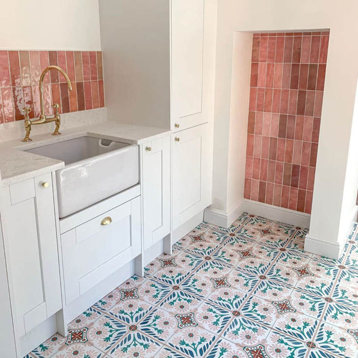 Zellij Rose Pink Brick Moroccan style tiles, 6.5cm x 20cm, vertical brick layout with warm rose pink and blush tones, natural tonal variation, glossy glazed finish, Moroccan-inspired design, kitchen setting with white cabinetry and patterned floor tiles.