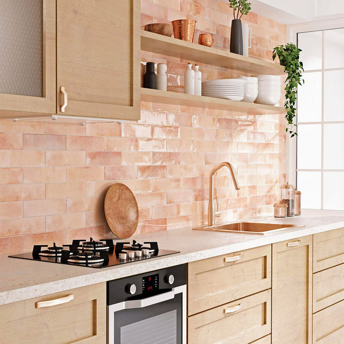 Izmir Brick Tusk Rose Gloss 6x25cm — featured in a warm, modern kitchen setting. These handcrafted glossy tiles bring a sunlit charm to interiors, blending blush and coral undertones for a naturally radiant finish. Perfect for brightening up backsplashes and feature walls with a soft, artisanal glow.