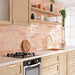 Izmir Brick Tusk Rose Gloss 6x25cm — featured in a warm, modern kitchen setting. These handcrafted glossy tiles bring a sunlit charm to interiors, blending blush and coral undertones for a naturally radiant finish. Perfect for brightening up backsplashes and feature walls with a soft, artisanal glow.
