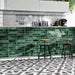 Contemporary kitchen featuring Izmir Brick Green Gloss 6x25cm ceramic wall tiles, styled with monochrome geometric floor tiles, white cabinets, and industrial bar stools for a bold modern look.