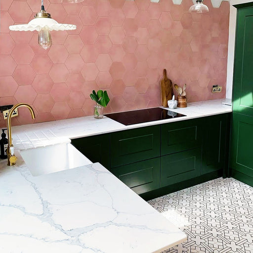 Alhambra Palacio 20x20cm Moroccan tiles in a modern kitchen setting featuring dark green cabinets, marble countertops, and pink hexagonal wall tiles, creating a bold yet elegant contrast with the geometric patterned floor.