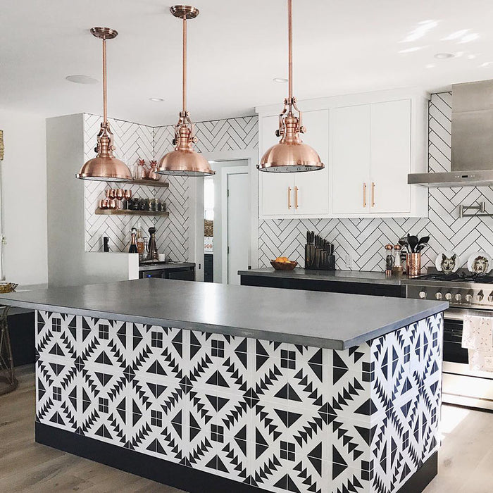 Alhambra Alkazar 20x20cm Moroccan tiles used on a modern kitchen island, featuring a bold black and white geometric pattern that contrasts beautifully with white cabinetry, copper pendant lights, and a sleek grey countertop.