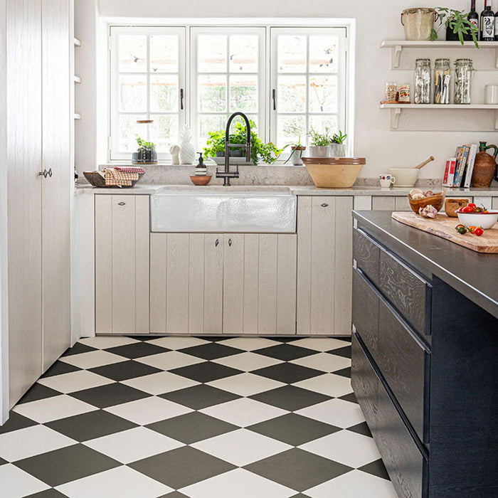 Kitchen featuring Chessboard Black 25×25cm Victorian-style porcelain floor tiles laid in a diagonal black-and-white chequerboard pattern, styled with light wood cabinetry, a farmhouse sink, open shelving, and a dark island for a modern country look.