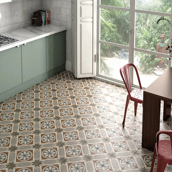 Kitchen featuring Carnaby Heythrop Victorian-style 20x20cm porcelain wall and floor tiles, showcasing a warm geometric and floral pattern in taupe, terracotta, and blue tones, styled with sage green cabinetry, marble countertops, and large garden-facing windows.