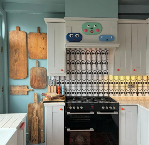 Alhambra Felisa 20x20cm Moroccan tiles used as a kitchen splashback, featuring a black and white geometric teardrop pattern paired with pale blue walls, wooden chopping boards, and light grey cabinets for a stylish modern-Moroccan look.