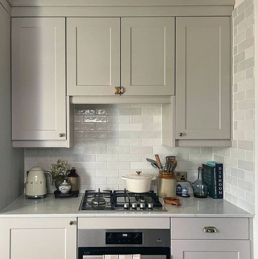 Kitchen splashback featuring Zellij White Gloss Brick Moroccan-style tiles in a 6.5cm x 20cm format, with a glossy white glaze and subtle handmade texture, paired with shaker-style cabinetry, a marble-effect worktop, and classic kitchen accessories.