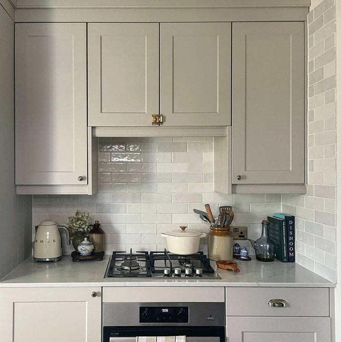 Kitchen splashback featuring Zellij White Gloss Brick Moroccan-style tiles in a 6.5cm x 20cm format, with a glossy white glaze and subtle handmade texture, paired with shaker-style cabinetry, a marble-effect worktop, and classic kitchen accessories.