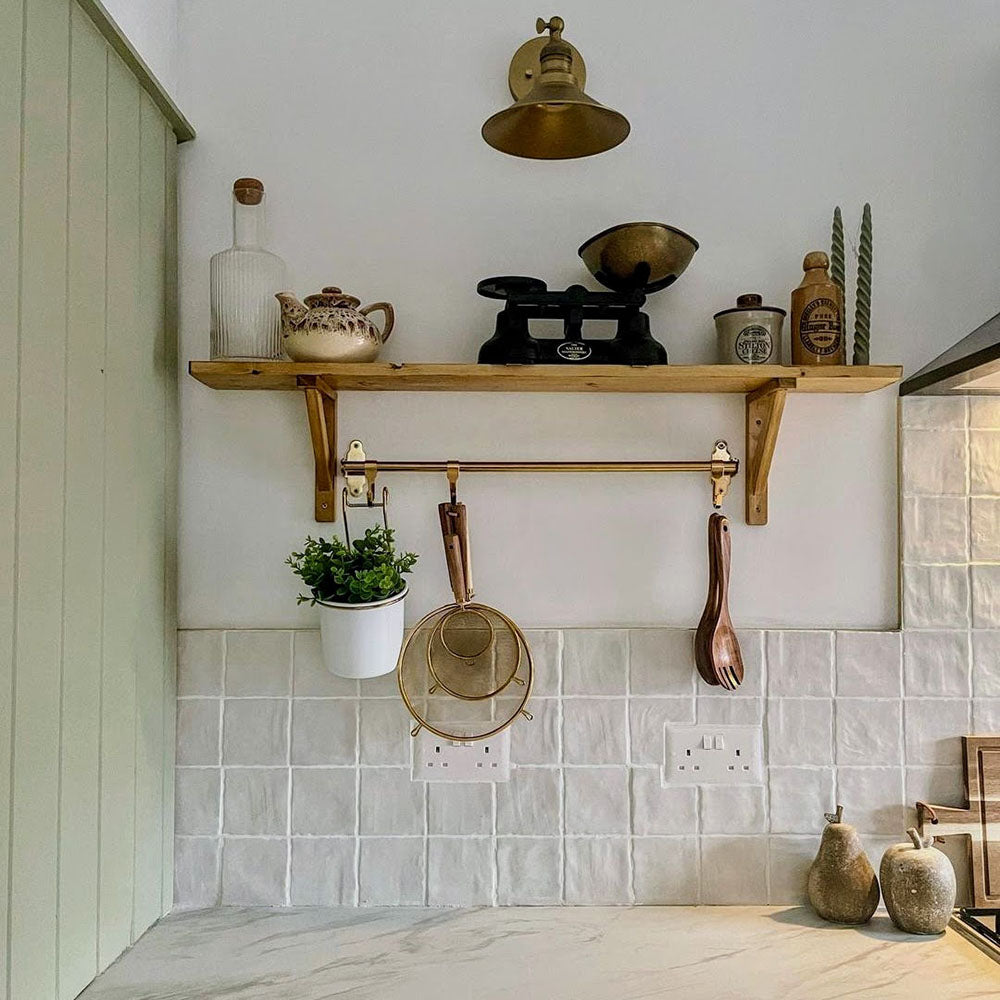 Kitchen interior featuring Zellij Oyster 10x10cm Moroccan-style square tiles in soft off-white tones, installed as a splashback, styled with warm wood shelving, brass accents, and neutral accessories for a calm, timeless look.