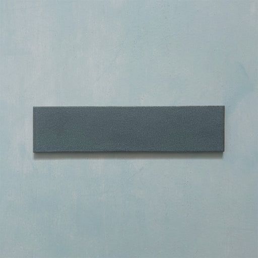 Single Kutani Laguna Blue 9.1cm x 37.5cm porcelain wall and floor tile, featuring a deep blue-grey finish with subtle tonal variation and softly irregular edges.