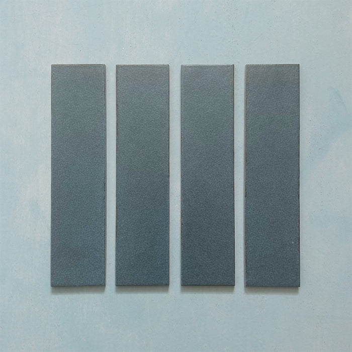 Kutani Laguna Blue 9.1cm x 37.5cm porcelain wall and floor tile, featuring a deep blue-grey finish with subtle tonal variation and softly irregular edges.