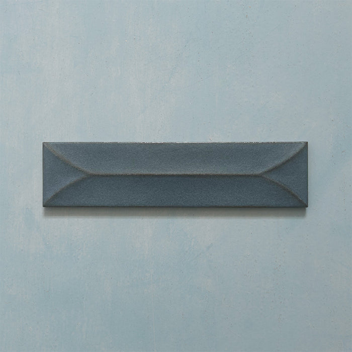 Single Kutani Decor Laguna Blue 9.1cm x 37.5cm porcelain wall tile, featuring a deep blue-grey finish with raised geometric detailing, subtle tonal variation and softly irregular edges.