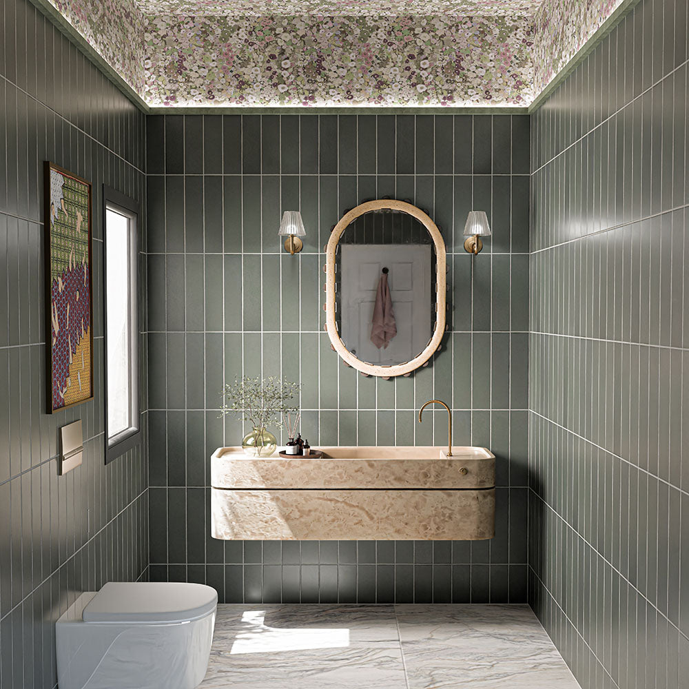Kutani Lichen Green 9.1cm x 37.5cm porcelain tiles, laid vertically across the walls to create an enveloping wash of muted green, balanced by warm stone details and a statement floral ceiling.