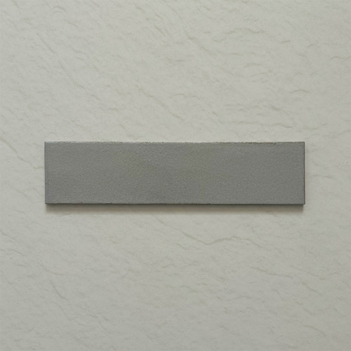 Single Kutani Lichen Green 9.1cm x 37.5cm porcelain wall and floor tile, featuring a muted grey-green finish with subtle tonal variation and softly irregular edges.