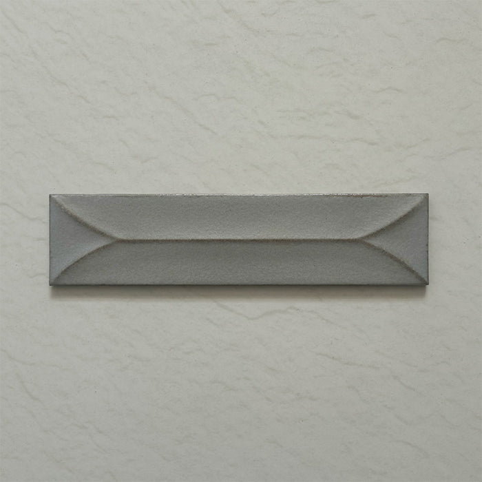 Single Kutani Decor Lichen Green 9.1cm x 37.5cm porcelain wall tile, featuring a muted grey-green finish with raised geometric detailing, subtle tonal variation and softly irregular edges.