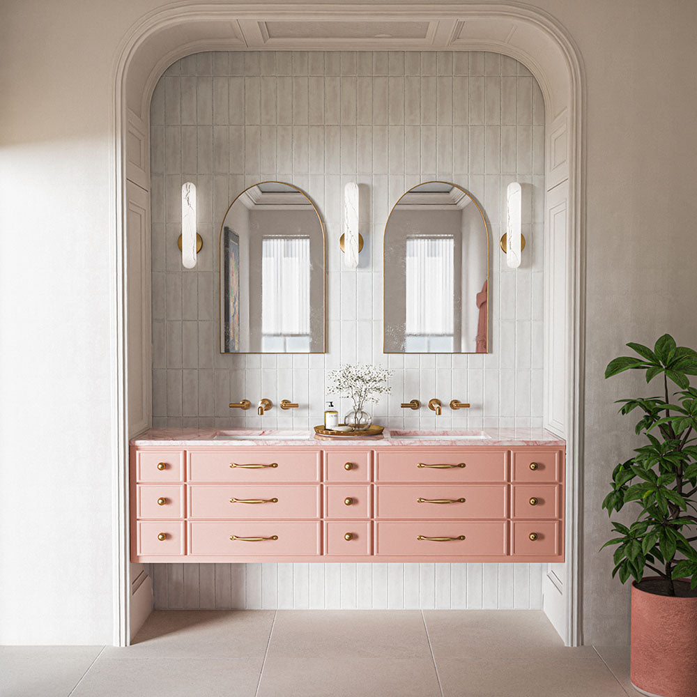 Elegant bathroom featuring Kyoto White 6.5x20cm Moroccan handmade-effect wall tiles, laid vertically behind a pink double vanity with marble-effect worktops, arched mirrors, brass fittings and soft neutral floor tiles.