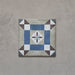 Single tile from the Carnaby Lane Victorian-style collection, 20x20cm porcelain wall and floor tile, featuring a blue and taupe geometric border with a central floral motif on an aged neutral background.
