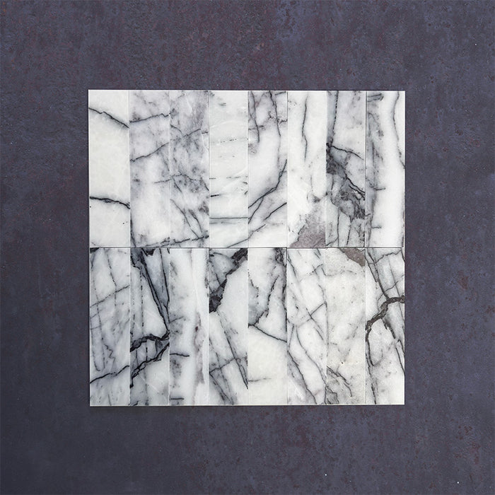 Group of Fitzrovia Lilac 5 x 20cm honed natural marble tiles arranged to showcase variation, featuring a soft white base with distinctive lilac-grey veining and natural tonal movement in a clean product setting.