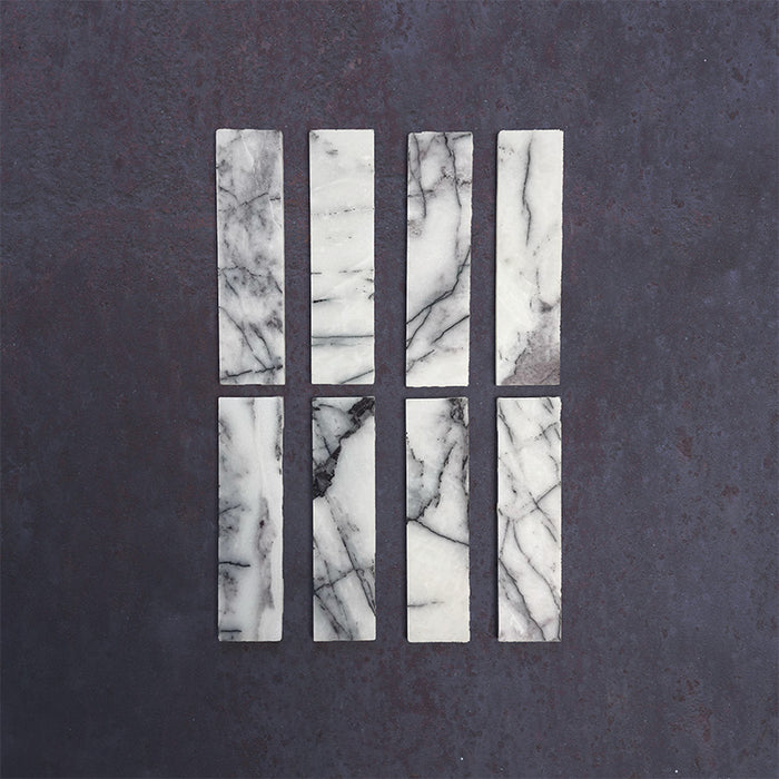 Group of Fitzrovia Lilac 5 x 20cm honed natural marble tiles arranged to showcase variation, featuring a soft white base with distinctive lilac-grey veining and natural tonal movement in a clean product setting.