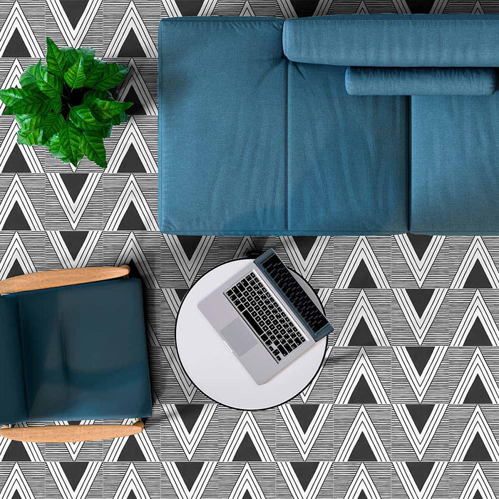Living room styled with Alhambra Pyramid 20x20cm Moroccan tiles featuring bold black and white geometric triangles, paired with modern blue furniture, a laptop on a round table, and a green plant for a fresh, contemporary look.