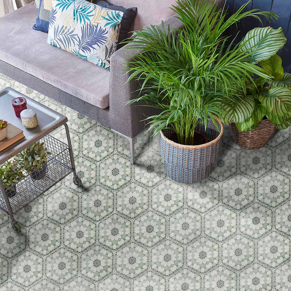Maroush Green 18.7x21.6cm Moroccan tiles used in a living room setting, featuring intricate geometric floral patterns in soft green and white tones beneath a grey sofa and lush potted plants for a fresh, elegant look.