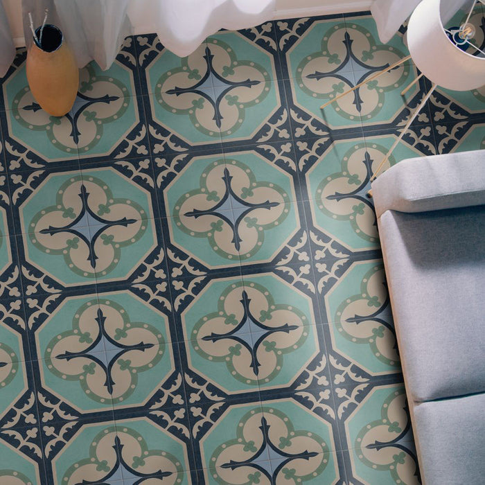 Living room interior featuring Europa Gothenberg 20x20cm Victorian Moroccan style floor tiles in blue, mint green and cream tones, styled with a grey sofa, floor lamp, curtains and decorative vase in a bright interior setting.