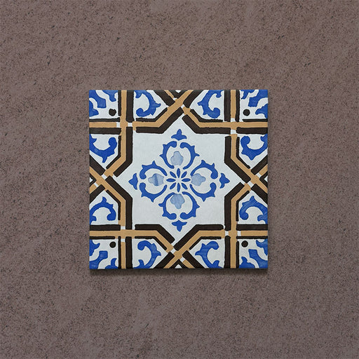 Single tile from the Carnaby Maestro Victorian-style collection, 20x20cm porcelain wall and floor tile, featuring an intricate blue floral motif framed by mustard and black geometric borders on an aged white background.