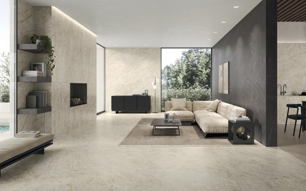 Open-plan living space featuring Grand Mahal Matt Marble effect 60 × 60cm porcelain wall and floor tiles, showcasing a soft ivory base with subtle beige and gold veining, paired with neutral furnishings, dark accent walls, and minimalist styling for a calm, contemporary finish.