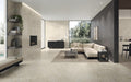 Open-plan living space featuring Grand Mahal Matt Marble effect 60 × 60cm porcelain wall and floor tiles, showcasing a soft ivory base with subtle beige and gold veining, paired with neutral furnishings, dark accent walls, and minimalist styling for a calm, contemporary finish.