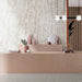 Interior setting featuring Grand Mahal Polished Marble effect 60 × 120cm porcelain wall and floor tiles, styled with a blush-toned counter, sculptural accessories, and soft lighting to highlight delicate veining and warm neutral tones.