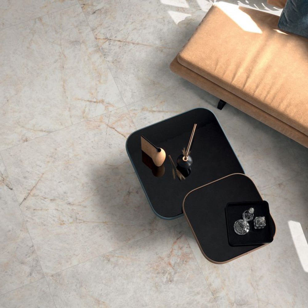 Living room featuring Grand Mahal Polished Marble effect 60 × 60cm porcelain wall and floor tiles, styled with soft neutral seating, black nesting tables, and warm natural light highlighting subtle veining.