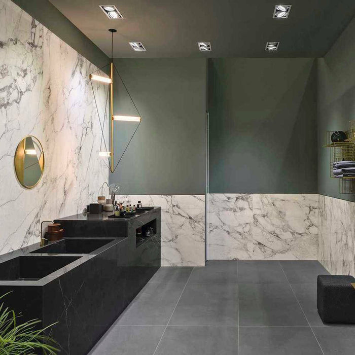 Bathroom interior featuring Maine Calacatta Matt Marble 30 × 60cm porcelain wall tiles, showcasing a clean white base with soft grey veining, paired with deep green walls, black vanity units, and warm brass lighting for a refined, contemporary contrast.