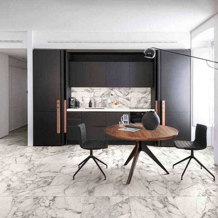 Modern kitchen and dining space featuring Maine Calacatta Matt Marble 60 × 60cm porcelain floor tiles, showcasing a crisp white base with soft grey veining, paired with dark cabinetry, warm wood tones, and minimalist styling for a clean, contemporary finish.