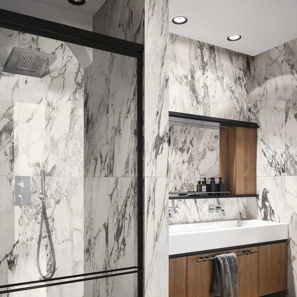 Bathroom interior featuring Maine Capraia Matt Marble 60 × 120cm porcelain wall tiles, showcasing a crisp white base with bold, dramatic grey veining, paired with black-framed shower detailing and warm wood cabinetry for a striking, contemporary contrast.
